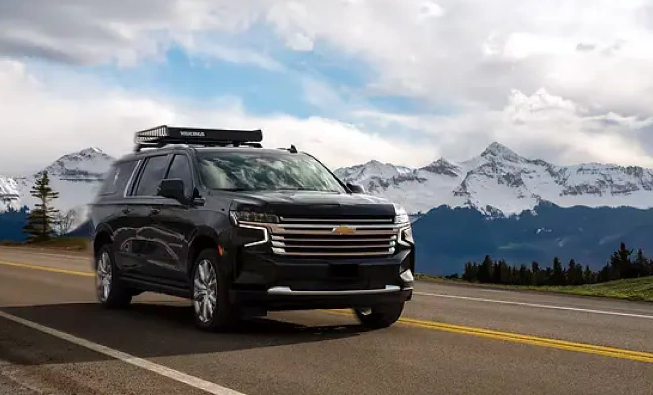 A black SUV with a roof box on a mountain road