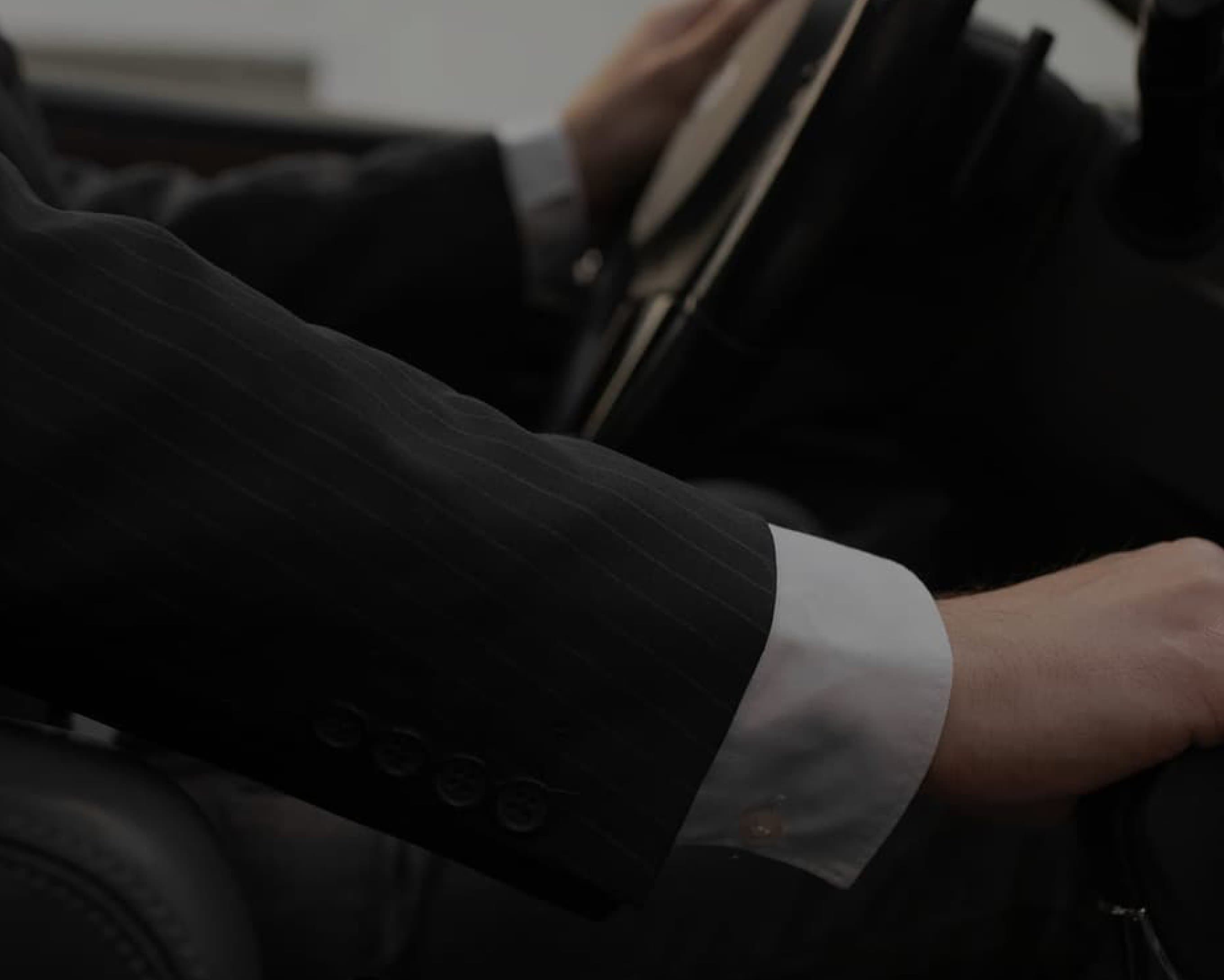 A chauffeur's hand on the steering wheel