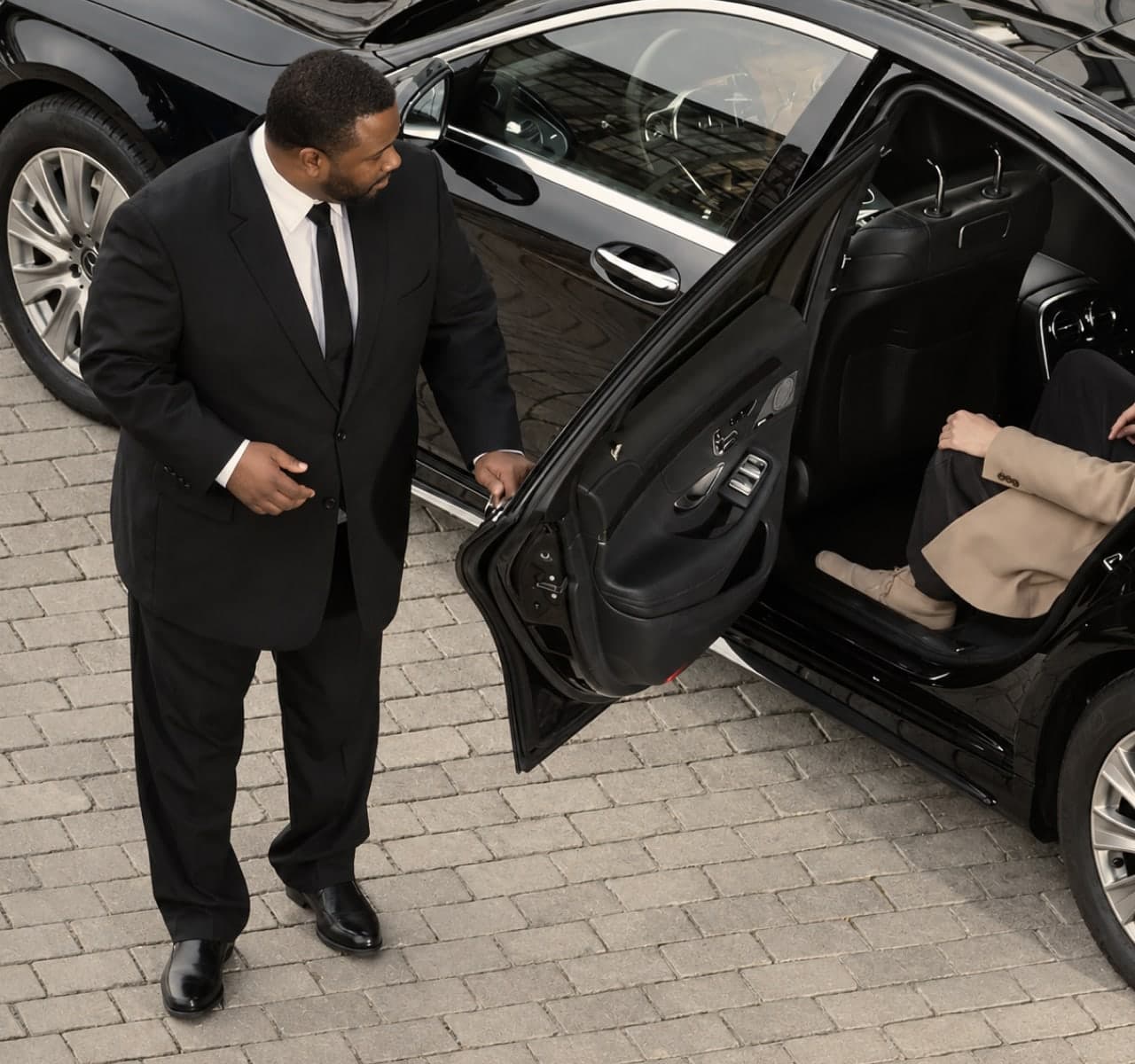 A chauffeur holding the rear door open for a passenger